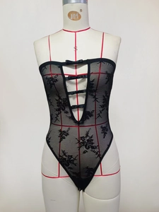 Dettaglio di un body in pizzo nero con ricami floreali e fiocchi decorativi in raso
