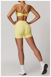 Dettaglio del reggiseno sportivo giallo incrociato e degli shorts fitness a vita alta