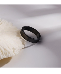 Detail view of a matte black minimalist adjustable open ring on a coral texture base