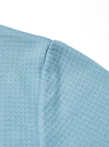 Detailed close-up showing the fine knitted texture and seams of the light blue polo shirt