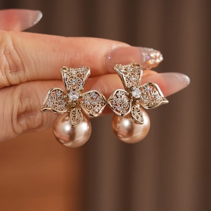 Gros plan sur boucles d'oreilles fleur dorée avec zircone et grande perle ronde