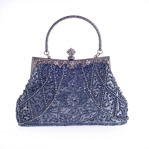 Dettaglio macro di ricami in perline blu e motivi floreali su borsa da sera vintage