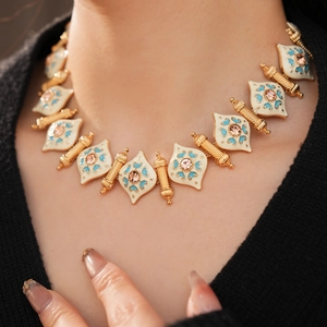Detail of vintage necklace with enamel rhombus patterns and pink rhinestones on a golden chain