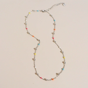 Minimalist stainless steel necklace with colorful round beads on a warm beige background