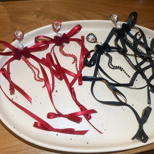 Détail de boucles d'oreilles nœud en velours avec strass, rubans de soie et perles