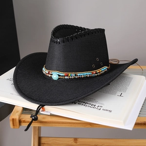 Détail d'un chapeau de cowboy noir en paille avec des perles bohèmes et pierre turquoise