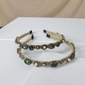 Detail view of vintage baroque headbands with emerald crystals and white pearls on gold wire