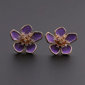 Dettaglio degli orecchini a fiore in smalto viola con bordi dorati e zirconi