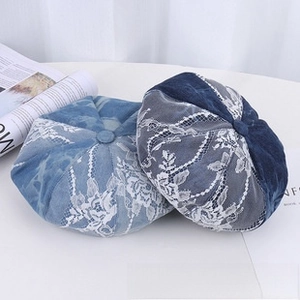 Detailed view of light and dark blue denim berets with white floral lace embroidery