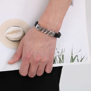 Detail of men's braided leather bracelet with silver steel Cuban chain on male wrist
