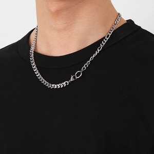 Gros plan d'un collier en maille gourmette et Figaro argenté sur un t-shirt noir