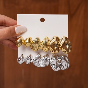 Detail of geometric wave-patterned earrings in gold and silver metal finishes
