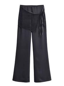 Détail du pantalon noir à taille haute avec superposition de dentelle et ruban latéral