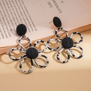 Detail view of flower-shaped zebra print fabric earrings with gold metal on a book