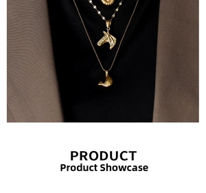 Close-up of layered 18K gold-plated necklaces with horse and fish charms on a dark blazer