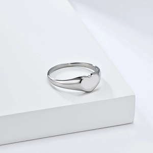 Minimalist heart-shaped titanium steel ring on a clean white geometric pedestal
