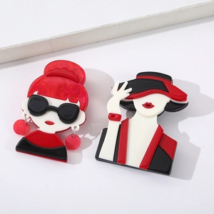 Close-up of creative acrylic cartoon girl brooches in stylish red and black colors