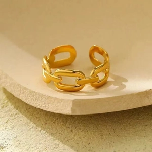 Macro detail of adjustable gold chain-link ring resting on natural sandstone texture