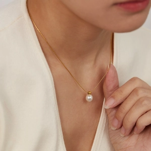 Minimalist gold pearl necklace on model neck featuring round white pearl pendant charm