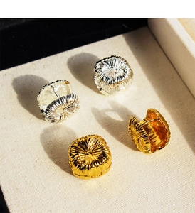 Macro view of textured fireworks pattern on gold and silver round disk earrings