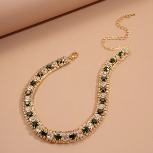 Detail of luxury gold necklace with green and clear crystals in vintage geometric style