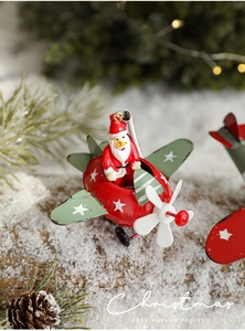 Close-up of vintage red iron airplane Christmas ornament with Santa Claus on snowy wood