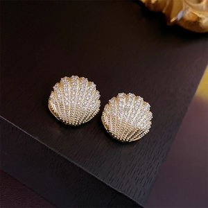 Macro shot of gold shell earrings with micro-pave cubic zirconia on wood background