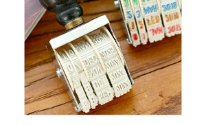 Detail of vintage rolling date stamp with metal frame and rubber dials on wood surface