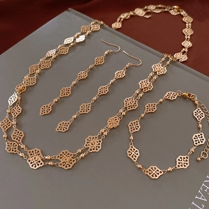 Close-up of gold clover jewelry set featuring detailed hollow floral lace craftsmanship