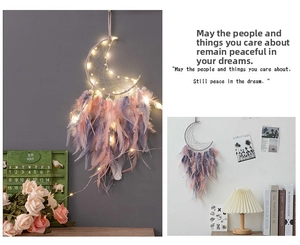 Detail of moon-shaped dream catcher with pink feathers and warm glowing LED lights