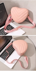 Detail of pink heart-shaped crossbody bag featuring V-quilt stitching and golden hardware