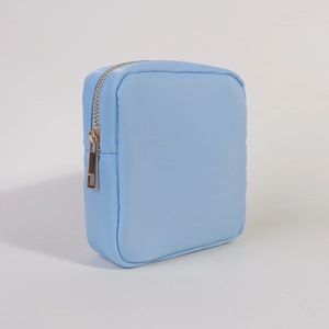 Close-up of light blue nylon cosmetic pouch with premium gold zipper on white background