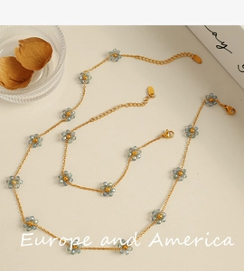 Detail of gold necklace set featuring blue crystal flower charms with lobster clasp