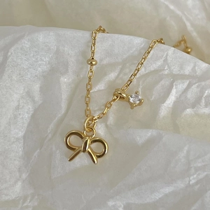 Elegant gold bow necklace featuring a sparkling round zircon pendant on a delicate chain