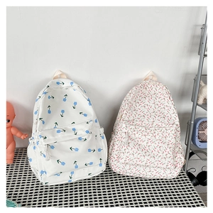 Detail shot of white fabric backpacks featuring blue tulip and pink floral patterns