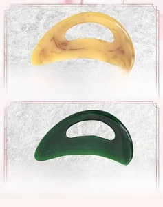 Detailed view of amber and green ergonomic resin scrapers for full body massage