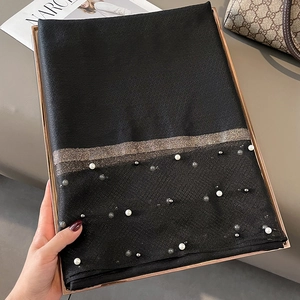 Detail of black silk shawl with pearl embellishments and luxury metallic gold thread