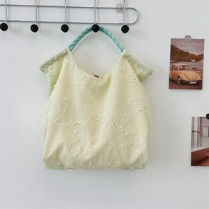 Detail of embroidered floral canvas tote with green and white rope handle on a wall hook