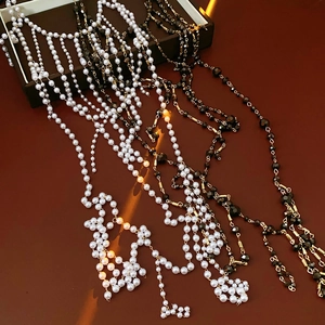 Detailed view of layered faux pearl and black faceted bead tassel necklaces on brown surface