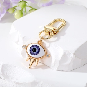Golden Evil Eye keychain with blue resin charm and crystals on white display block