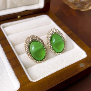 Macro detail of vintage green oval gemstone earrings with sparkling crystal halo