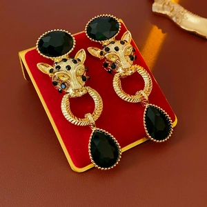 Detail of vintage leopard head earring with black water drop gemstone on red velvet stand