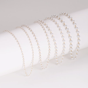 Multilayer stainless steel necklace with white pearls on a gold chain displayed on a stand