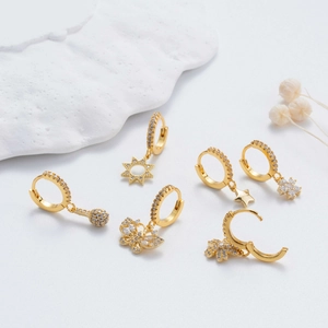 Golden hoop earrings set with zircon star and flower charms on elegant white background