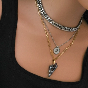 Close-up of layered silver coin pendant and golden lightning charm necklace on model