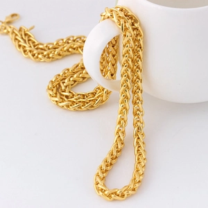Collier hip hop en acier inoxydable doré avec maille tressée sur un fond de tasse