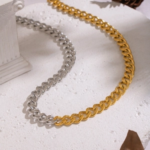 Macro shot of two-tone gold and silver Cuban link necklace on textured stone background