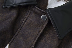 Macro detail of leopard print felt fabric with black leather collar and silver metal button