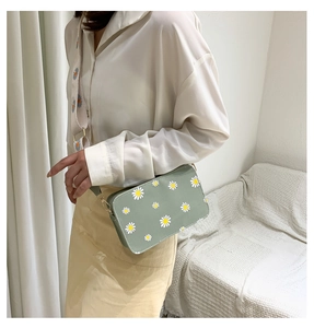 Detail of mint green crossbody bag with daisy floral print and embroidered wide strap