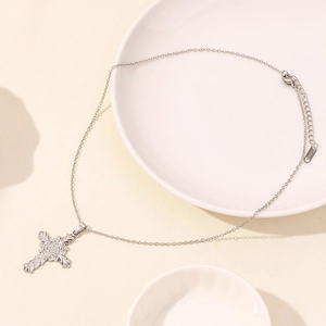 Detailed view of silver stainless steel rose cross necklace on white ceramic tray